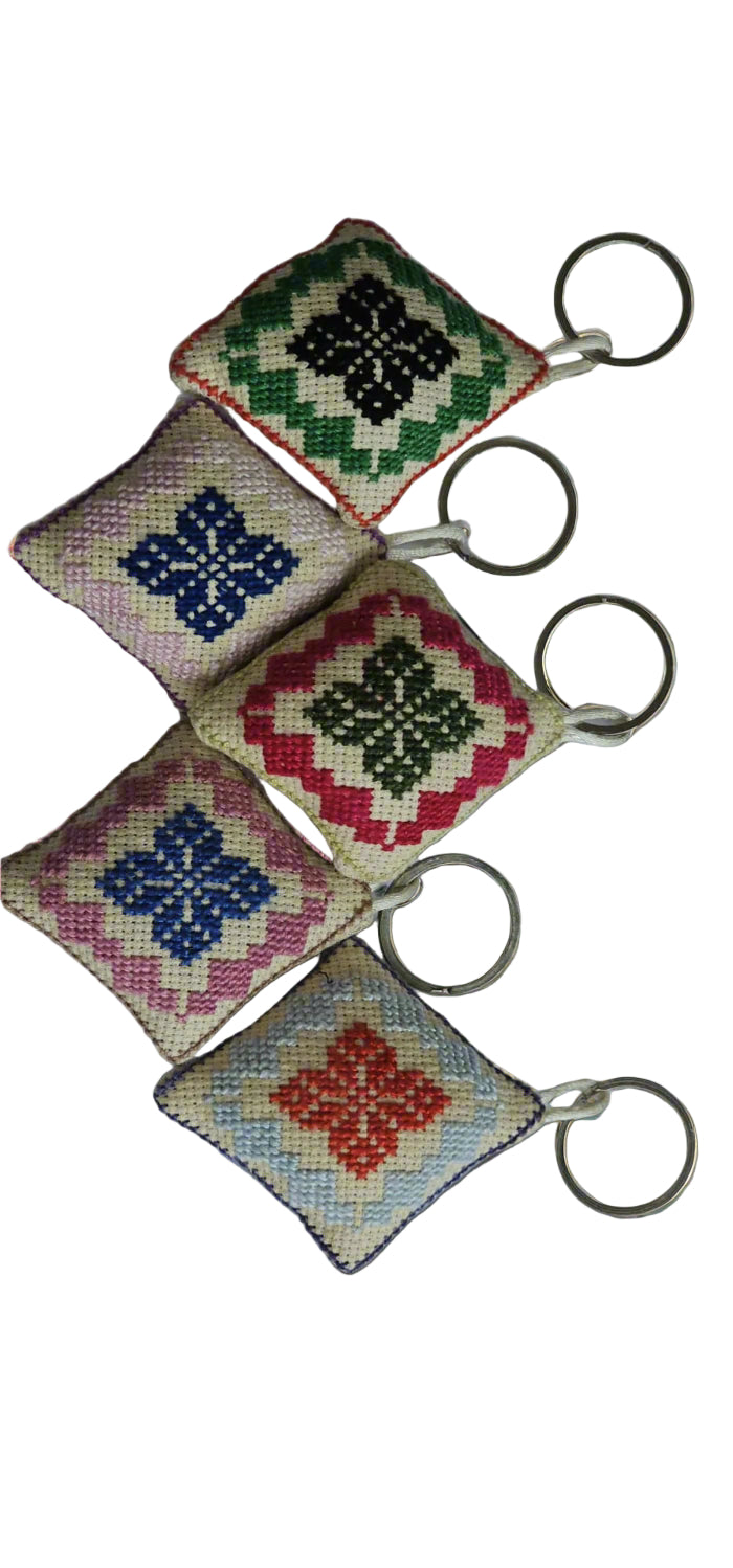 Four colorful cross-stitched keychains on a white background